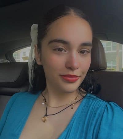 Portrait of a young woman with dark hair and red lipstick in a car.